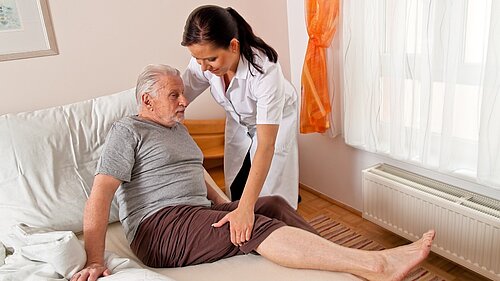 A nurse helping an old man get out of bed.